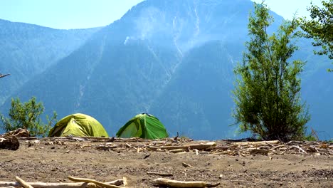 Two-tents-on-the-sandy-shore-of-the-lake-in-the-mountains.