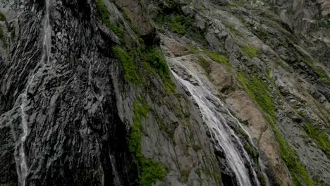 Tracking-and-top-shot-Air-shot-from-a-stream-of-water-splashing-waterfall-on-a-rock-wall-in-the-Caucasus-Mountains.-Around-the-jet-of-the-waterfall