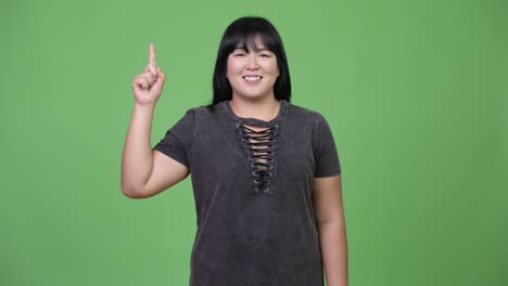 Happy-overweight-Asian-woman-pointing-finger-up