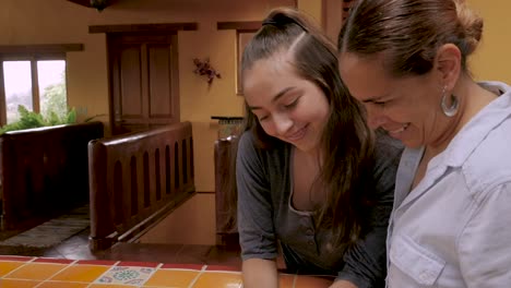 Hispanic-mother-and-daughter-take-selfies-and-look-at-them-on-their-cell-phone