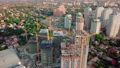 Aerial-drone-shot.-Construction-of-high-rise-buildings-in-the-developing-area-of-a-large-city.-Sunset-shot.-Span-above-the-construction-site.-go-from-wide-shot,-pull-back-to-a-close-up