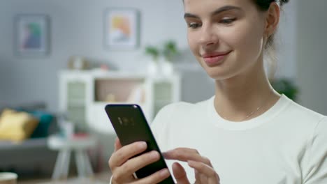 Retrato-de-la-hermosa-joven-mujer-utilizando-Smartphone,-navegando-en-Internet,-revisar-redes-sociales-mientras-se-sienta-en-casa.