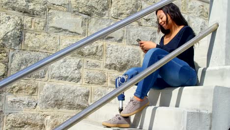 Side-view-of-disabled-woman-texting-on-mobile-phone-at-stairs-4k