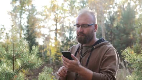 Young,-bearded-guy-holding-a-phone-and-presses-the-screen