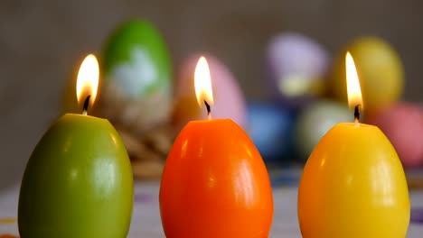 Velas-hechas-en-forma-de-huevo-de-Pascua.-Quemando-velas.-Verde,-naranja,-amarillo.-Huevos-de-Pascua-velas-y-coloridos-huevos-de-Pascua-en-el-fondo.