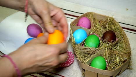 Woman-puts-colorful-Easter-eggs-in-basket-with-hay.