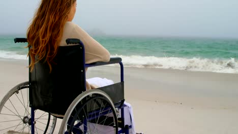 Blick-auf-Frau,-die-auf-dem-Rollstuhl-am-Strand-4k-sitzt