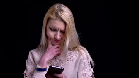 Closeup-portrait-of-middle-aged-caucasian-female-browsing-on-the-phone-and-reacting-to-social-media-posts-with-background-isolated-on-black