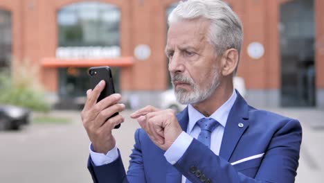 Outdoor-Portrait-of-Old-Businessman-Using-Smartphone