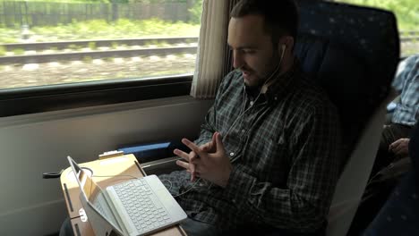 Man-chatting-with-his-laptop-in-a-train