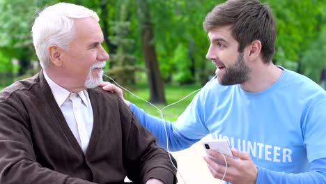 Divertido-hombre-voluntario-y-jubilado-discapacitado-escuchando-música-en-auriculares,-cuidado