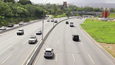 Many-cars-and-trucks-driving-on-road-in-a-large-modern-urban-city-area