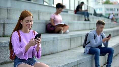 Estudiantes-universitarios-chateando-por-teléfonos-inteligentes,-adolescentes-que-se-desplazan-aplicación-de-la-red-social