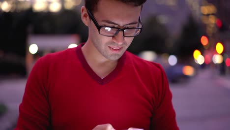 Handsome-spanish-male-blogger-in-eyeglasses-for-vision-correction-updating-notification-on-cellular-phone