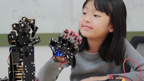 Little-Girl-is-playing-with-robotic-arm-in-a-school.-She-is-controlling-it-by-her-hand.