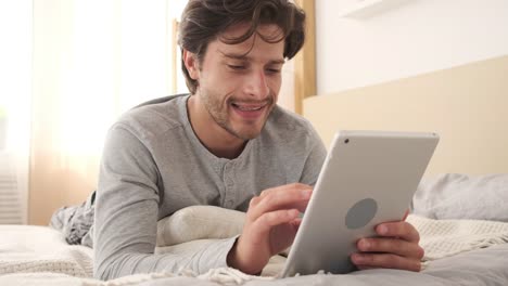 Man-using-digital-tablet-in-bed