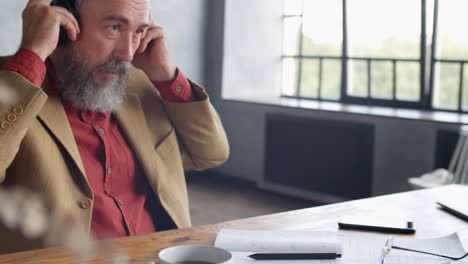 Hombre-Senior-guapo-usando-gadgets-en-la-oficina