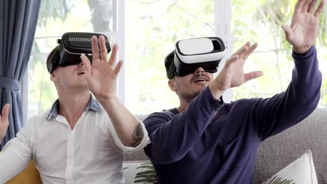 Schwules-Paar-entspannen-auf-der-Couch-mit-Virtual-Reality-Gerät.-Aufwärtsschuss.