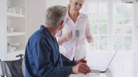 Pareja-de-la-tercera-edad-con-hombre-en-silla-de-ruedas-buscando-información-sobre-medicamentos-en-línea-usando-computadora-portátil