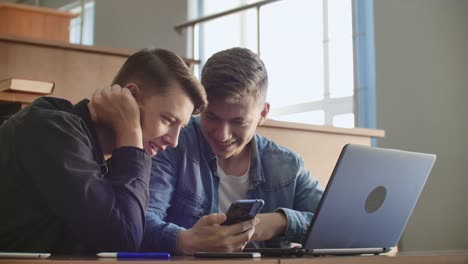 Hübsche-Mädchen-Studenten-sind-mit-DemSmartphone,-Beobachten-des-Bildschirms,-reden-und-lachen-sitzen-an-Den-Tischen-an-der-Universität.-Social-Media,-Internet,-Millennials-und-Bildungskonzept.