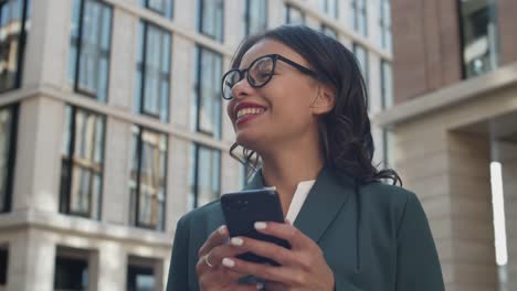 Cheerful-Businesswoman-Using-Cellphone-Outside