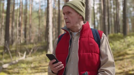 Sportliche-Senioren-mit-Telefon-im-Wald