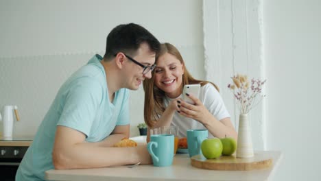 Cámara-lenta-del-hombre-y-la-mujer-usando-el-teléfono-inteligente-en-la-mesa-de-la-cocina-en-el-desayuno