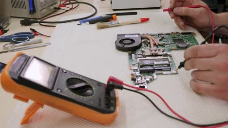 Close-up-of-technician-man-measuring-electrical-voltage-of-computer-mainboard.