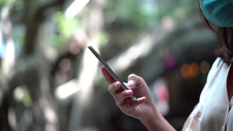 Young-asian-woman-wearing-protective-face-mask-and-using-smartphone