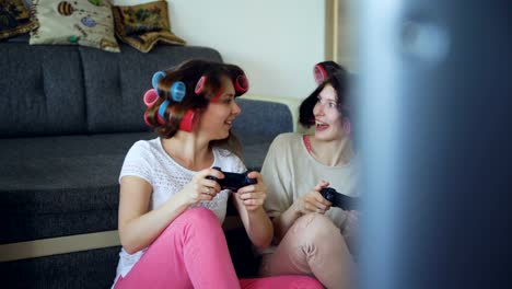 Zwei-lustige-Frauen-spielen-Konsolenspiele-mit-Gamepad-und-haben-Spaß-zu-Hause