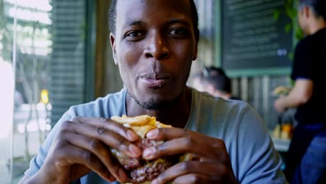 Happy-black-guy-laugh-and-eats-tasty-meat-burger