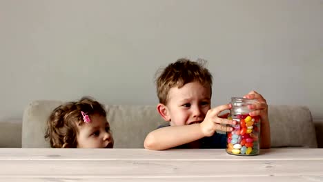 niedlicher-kleine-Junge-versucht-offene-Glas-mit-bunten-Süßigkeiten