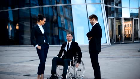 Empresario-de-lisiado-en-silla-de-ruedas-y-dos-sus-colegas-tiene-conversación-positiva