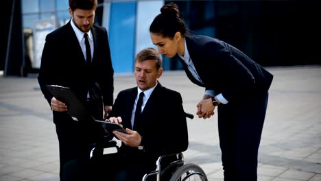 Young-disabled-businessman-talking-with-his-coworkers