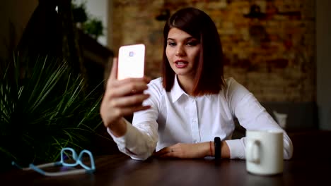 Casual-young-woman-talking-on-phone-having-conversation-via-video-chat-conference-at-home-office.-Businesswoman-using-smart-phone-app-on-smartphone-smiling-happy