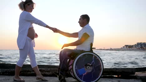 discapacitados-y-esposa-bailando-en-pareja-tarde,-inválido-en-silla-de-ruedas-con-mujer-embarazada-al-atardecer