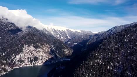 Panoramic-view-of-beautiful-white-winter-wonderland-scenery-with-snowy-mountain-summits.-Clip.-Crystal-clear-mountain-lake-on-a-cold-sunny-day-with-blue-sky-and-clouds