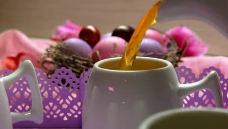 ein-Tee-in-der-Tasse-auf-dem-Hintergrund-von-farbigen-rosa-Osterei-Lügen-gegossen