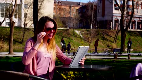 Chica-Gladden-hacer-video-llamada-por-tableta-al-novio-en-el-parque-y-la-mano-que-agita