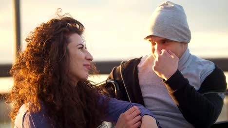 Happy-couple---disabled-man-in-wheelchair-talking-with-attractive-young-woman-enjoing-the-sunset