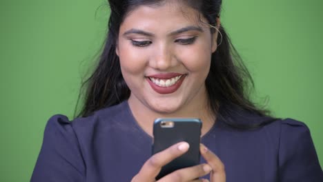 Young-overweight-beautiful-Indian-businesswoman-against-green-background