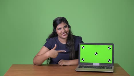 Young-overweight-beautiful-Indian-businesswoman-against-green-background