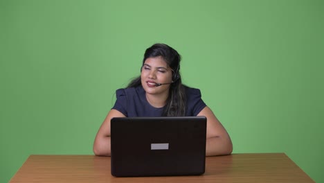 Young-overweight-beautiful-Indian-businesswoman-against-green-background