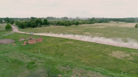 Aerial-Drone-footage.-Fly-over-abandoned-farm-to-rally-car-on-road