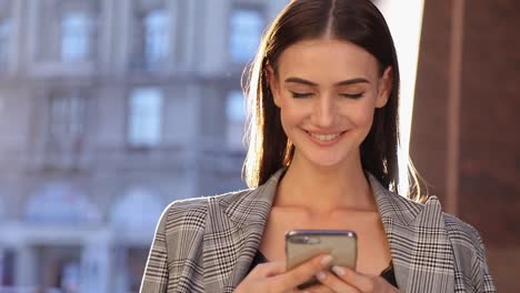 Schöne-Geschäftsfrau-mit-Handy-im-Freien-an-sonnigen-Tag