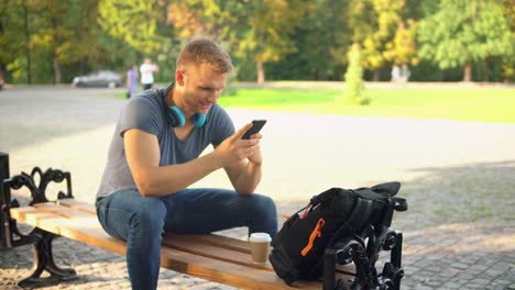 caucasian-guy-messaging-text-on-mobile-at-the-open-air