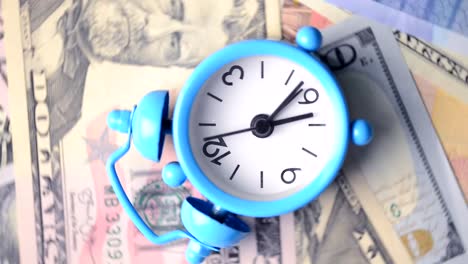 VIDEO,-Classic-alarm-clock-rotating-on-a-pile-of-cash-banknotes