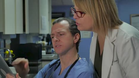 Female-and-male-doctors-pointing-at-a-digital-tablet-in-a-medical-facility