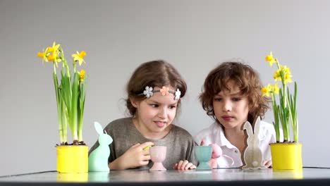 Niños-divertidos,-un-chico-y-una-chica-leerlo-de-la-mesa-con-una-decoración-de-Pascua.-Búsqueda-de-huevos-de-Pascua