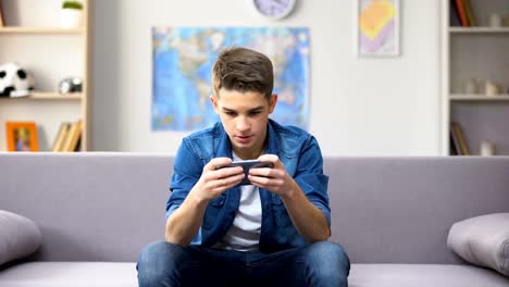 Gadget-addicted-Caucasian-teenager-playing-game-on-smartphone,-wasting-time